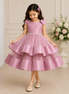 Young girl in a pink dress with a floral arrangement in the background