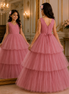 Young girl in a pink dress standing in front of a mirror in an elegant room.