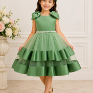 Young girl wearing a green dress with a floral arrangement in the background