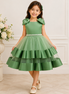 Young girl wearing a green dress with a floral arrangement in the background