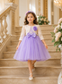 Young girl in a purple dress with a floral headband standing on a staircase.
