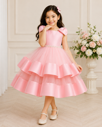 Young girl in a pink dress standing in a room with floral decorations.