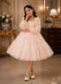 Young girl in a white dress standing in an elegant room with decorative furniture and flowers.