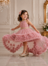 Young girl in a pink floral dress twirling in a grand room.