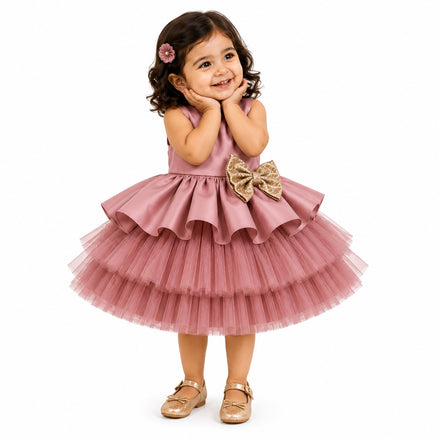Young girl wearing a pink dress with a large bow on a white background