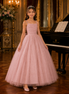 Young girl in a pink dress standing in a formal setting with a grand piano.