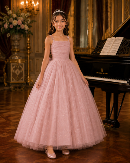 Young girl in a pink dress standing in a formal setting with a grand piano.