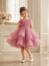 Young girl in a pink dress standing in a decorated room with flowers in the background