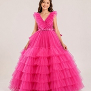 Young girl wearing a pink tiered dress on a plain background