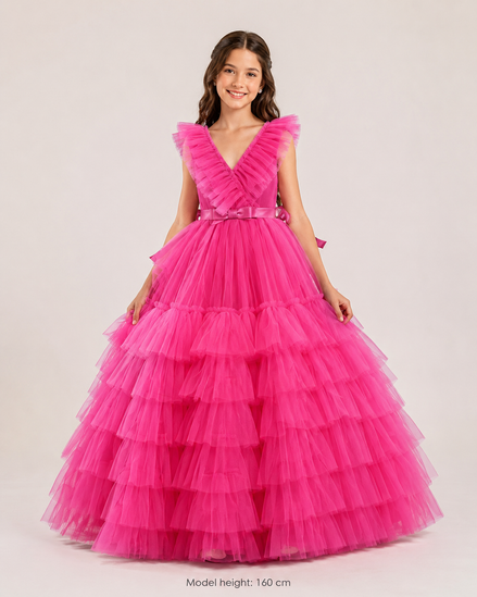 Young girl wearing a pink tiered dress on a plain background