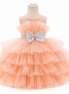 Peach-colored tiered dress with a large bow on a mannequin against a white background