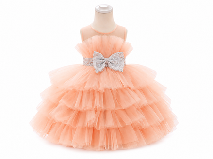 Peach-colored tiered dress with a large bow on a mannequin against a white background