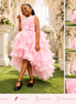 Young girl in a pink dress standing outdoors with floral decorations.