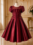 Burgundy evening gown on a mannequin against an elegant interior background