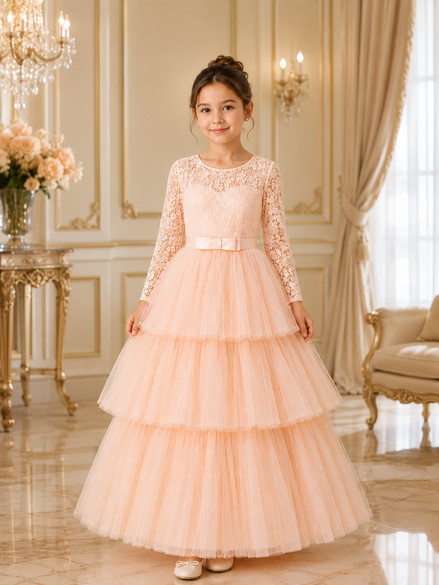 Young girl in a peach lace dress standing in an elegant room with chandelier and floral arrangement.
