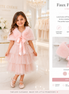 Young girl wearing a pink dress with a matching faux fur shawl in a store setting.