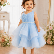 Child in a light blue dress standing in a decorated room with flowers.