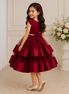 Young girl in a burgundy dress with a floral arrangement in the background
