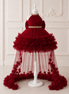 Red dress with floral details on a white mannequin against a white wall.