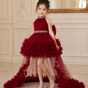 Young girl in a red dress with a decorative belt and long train in an elegant room.